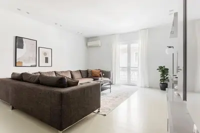 a living room with a brown couch in a white room at Contemporary Bliss 2BR Apartment in Athens by UPSTREET in Athens