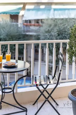 a table and chair on a balcony with orange juice at Nature-Infused Vibes & Nightlife in Athens