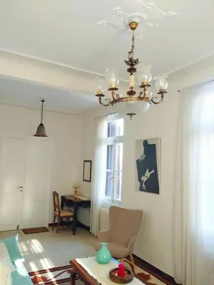 a living room with a chandelier and a table at Calliope's Neoclassical Home in the heart of Plaka in Athens