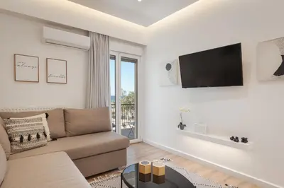 a living room with a couch and a tv on a wall at Glyfada Cozy Living in Athens