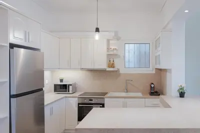 a kitchen with white cabinets and a stainless steel refrigerator at Glyfada Cozy Living in Athens