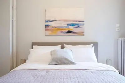 a bed with white pillows and a painting on the wall at Urban Oasis Terrace 2Bebroom apartment in Athens