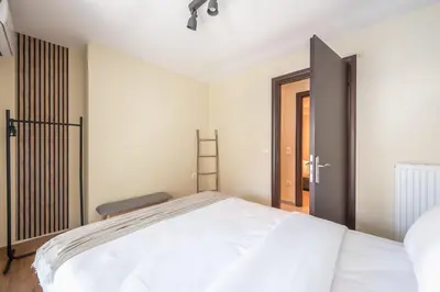 a bedroom with a large white bed and a chair at Artistic 2BR Maisonette: An Architectural Delight in Athens