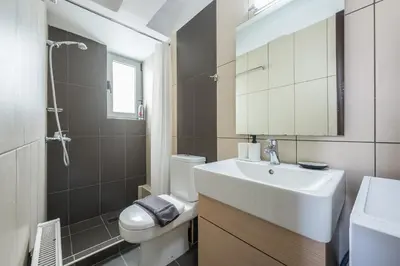 a bathroom with a sink and a toilet and a mirror at Artistic 2BR Maisonette: An Architectural Delight in Athens