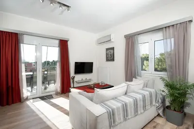 a living room with a white couch and a tv at Starfish Complex in Porto Rafti