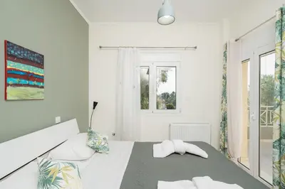 a white bedroom with a bed and a window at Starfish Complex in Porto Rafti