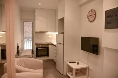 a kitchen with a living room with a clock on the wall at Lovely Apartment in Athens