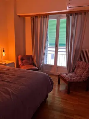 a bedroom with a bed and a chair and a window at 4th floor cosy apartment in Metaxourgeio in Athens