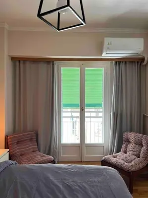 a bedroom with a bed and two chairs and a window at 4th floor cosy apartment in Metaxourgeio in Athens