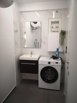 a small bathroom with a washing machine and a sink at Ground floor apt. with garden, Timfristou 86 Chalandri in Athens