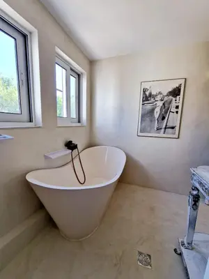 a large white tub in a bathroom with windows at Luxurious studio apartment close to the beach and airport in Porto Rafti