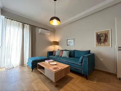 a living room with a blue couch and a table at Artist's 1 BD Apt in Keramikos in Athens