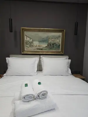a white bed with two rolled towels on it at DIONE Luxury Business Suite in the heart of Athens in Athens