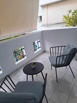a patio with two chairs and a table and two windows at Spata Airside Apartment in Spáta