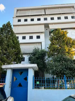 a white building with a blue door and a fence at Spata Airside Apartment in Spáta