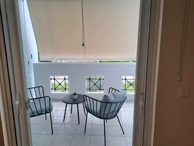 a room with chairs and a table and windows at Spata Airside Apartment in Spáta
