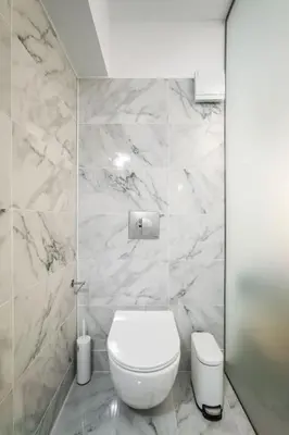 a bathroom with a white toilet and marble walls at modern boutique apartment in Athens