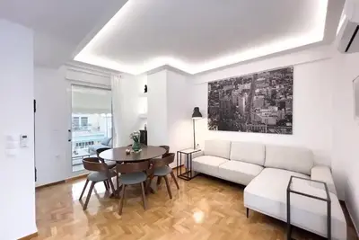 a living room with a white couch and a table at Spacious Penthouse near Downtown in Athens