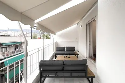 a balcony with a couch and tables on a building at Spacious Penthouse near Downtown in Athens
