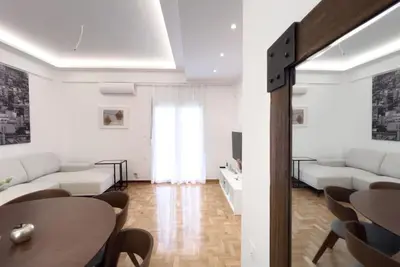 a living room with white furniture and a table at Spacious Penthouse near Downtown in Athens