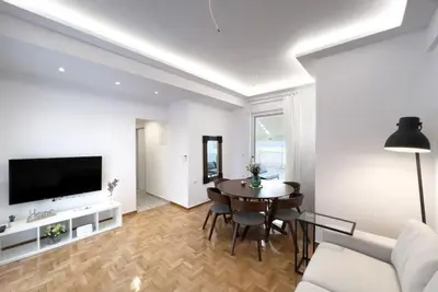 a living room with a table and a tv at Spacious Penthouse near Downtown in Athens