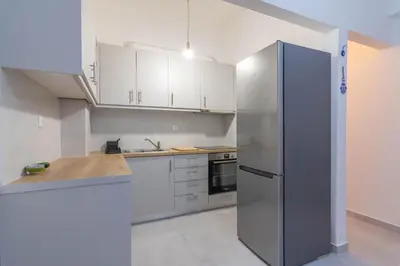 a kitchen with white cabinets and a stainless steel refrigerator at ARIS Patisia in Athens