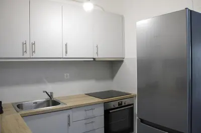 a kitchen with white cabinets and a stainless steel refrigerator at ARIS Patisia in Athens