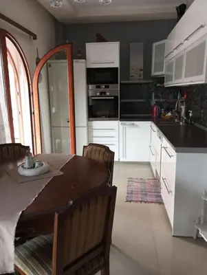 a kitchen with white cabinets and a table and chairs at Κατερινα in Athens