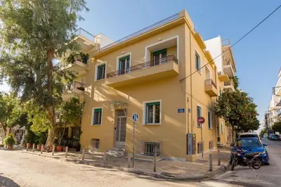 a yellow house with a motorcycle parked in front of it at Troon of Athens House in Athens