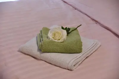 a white rose sitting on a pile of towels on a bed at Citrus dream apartment in Athens