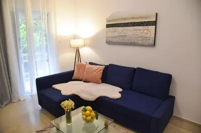 a blue couch in a living room with a glass table at Citrus dream apartment in Athens