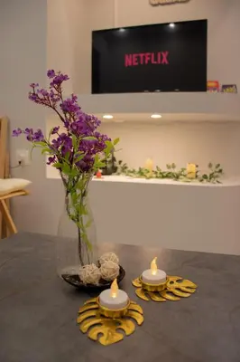 a vase with purple flowers sitting on a table with candles at Moon Haven Near Acropolis with 100Mbps WiFi in Athens