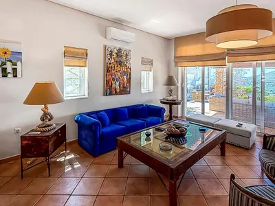 a living room with a blue couch and a table at Escape pool villa in Anavissos in Athens