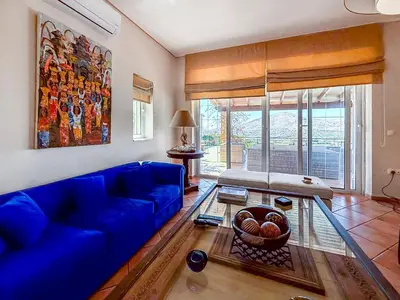 a living room with a blue couch and a glass table at Escape pool villa in Anavissos in Athens