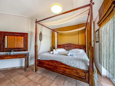 a bedroom with a wooden canopy bed and a table at Escape pool villa in Anavissos in Athens