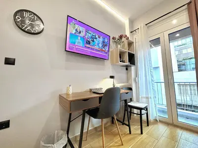 a desk with a chair and a clock on a wall at Elegant & Stylish 2nd Floor Flat - 3' from Metro in Athens