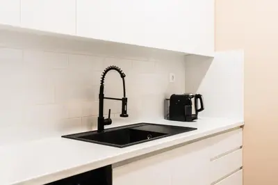 a kitchen with a black sink and white tiles at Snug by Zoia Living in Athens