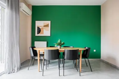 a dining room with a green wall and a wooden table and chairs at Snug by Zoia Living in Athens