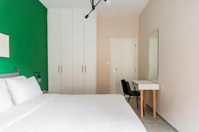 a bedroom with a white bed and a green wall at Snug by Zoia Living in Athens