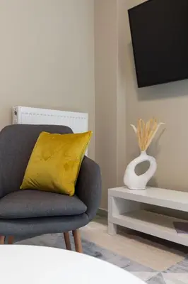 a living room with a chair and a yellow pillow at Snug by Zoia Living in Athens