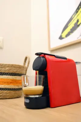 a red toaster sitting on top of a table with a glass at Cosy apartment in Glyfada in Athens