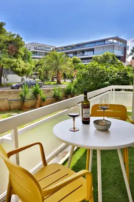 a table and chairs on a balcony with a bottle of wine at Cosy apartment in Glyfada in Athens