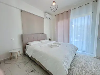 a white bedroom with a large bed and a window at Kasaj Luxury Apartments in Porto Rafti