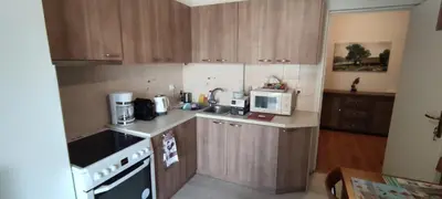 a kitchen with wooden cabinets and a stove and microwave at Spacious flat ideal for families in Athens