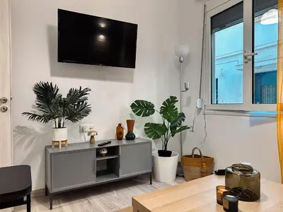a living room with plants and a tv on a wall at Kallithea Zen Studios-Near Filopappou & Koukaki in Athens