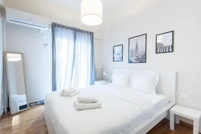 a white bedroom with a large white bed and a window at Superb Family Apt In The Center Of Athens in Athens