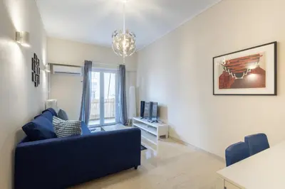 a living room with a blue couch and a tv at Superb Family Apt In The Center Of Athens in Athens