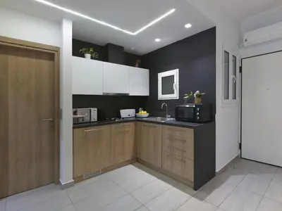 a kitchen with wooden cabinets and a black wall at Modern Haven near Archaeological Museum in Athens