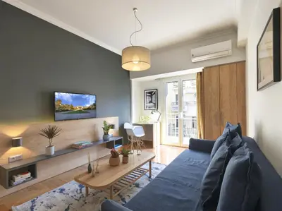a living room with a blue couch and a table at Modern Haven near Archaeological Museum in Athens
