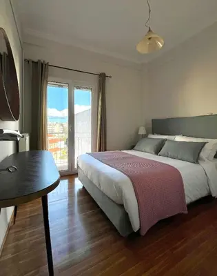 a bedroom with a bed and a table and a window at Bright 2 bdr Pagrati apartment in Athens